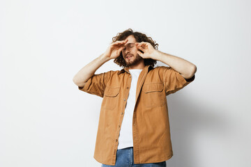 Young man with curly hair expressing frustration while wearing a casual brown shirt, against a...
