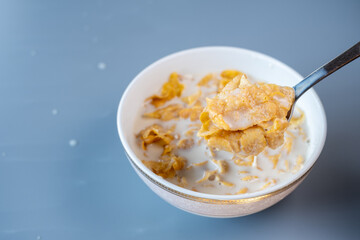 A spoon lifting a portion of crispy cornflakes soaked in milk from a bowl