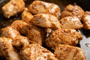 Chicken fillet pieces are fried in a frying pan in sauce