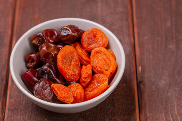 Dried dates and apricots in a bowl on a wooden table iftar suhoor month of ramadan. copy space