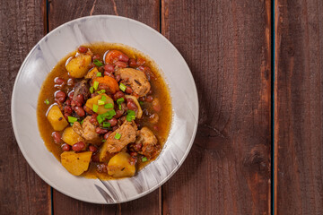 On the plate on the table is chelnt with potatoes, beans, onions, meat, spices