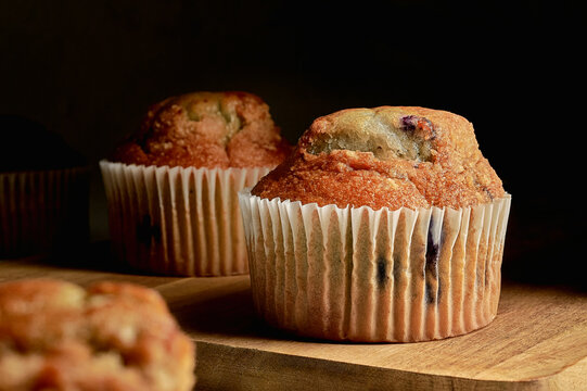 Muffins de ar&aacute;ndanos con iluminaci&oacute;n dram&aacute;tica y fondo oscuro