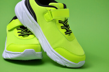 A pair of stylish green sneakers on a green background. Close-up.