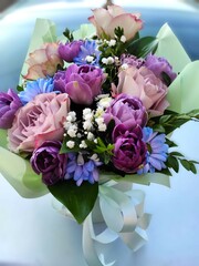 bouquet of blue, purple, white flowers in green packaging close up.

