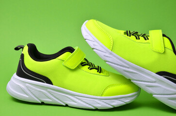 A pair of light green sneakers on a green background. Minimal photo of sports shoes