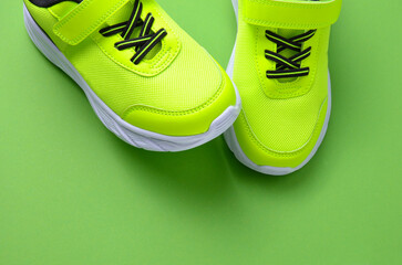 Pair of stylish green sneakers on a green background.