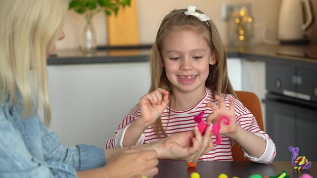 Happy family fun make together diy from colored chenille wire toys. Mother and little daughter create handmade craft. Leisure with children