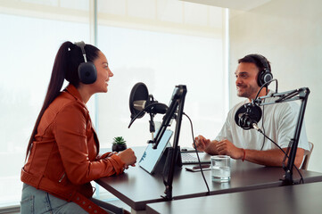 Podcasters creating audio content, talking and smiling during a live recording session