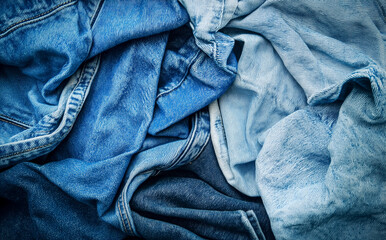 Various shades of blue denim fabric arranged in a textured pile showcasing different styles and washes