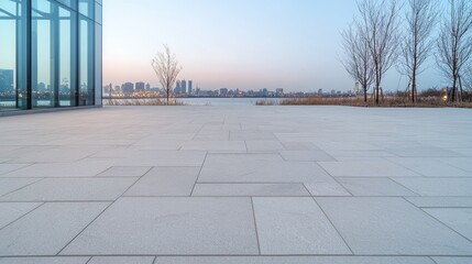 Obraz premium Empty plaza by water at dawn, modern city skyline. Possible use stock photo