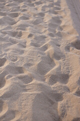 Dry beach sand with footprints and shoe soles.