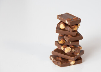 pieces of chocolate with nuts are folded one by one in a pyramid on a white background