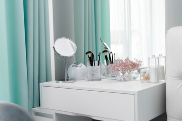 Makeup brushes are in a standing vase on a dressing table. The design of the dressing table is in an elegant modern bedroom. Makeup corner in the bedroom. Interior Minimalist Design
