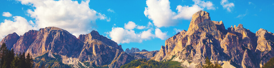 Mountains ridge against blue sky with clouds at daylight on a sunny day. Beautiful mountain landscape. View from Sella pass, Dolomites Alps, Italy Europe. Horizontal banner