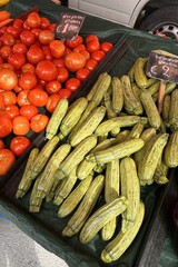 Fresh red tomatoes and green zucchinis on a market stall, priced