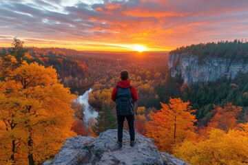 Obraz premium Person enjoys a breathtaking sunset view overlooking a forested landscape with vibrant autumn colors