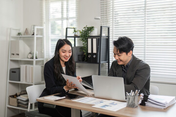 Business professionals collaborating and reviewing reports together at a desk in an office.