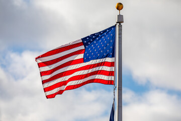 American flag waving with clouds in the background