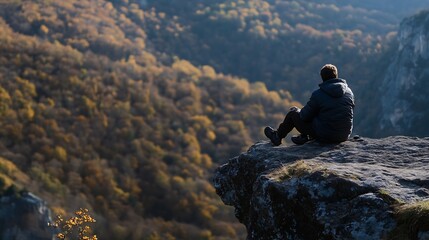 Solitary figure on rocky ledge overlooking vibrant autumn valley landscape during golden hour : Generative AI
