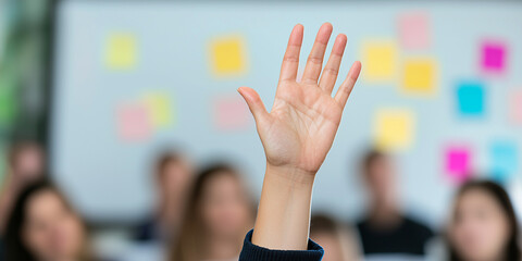 Hand raised in classroom setting to ask question during interactive learning session with students and colorful sticky notes on background