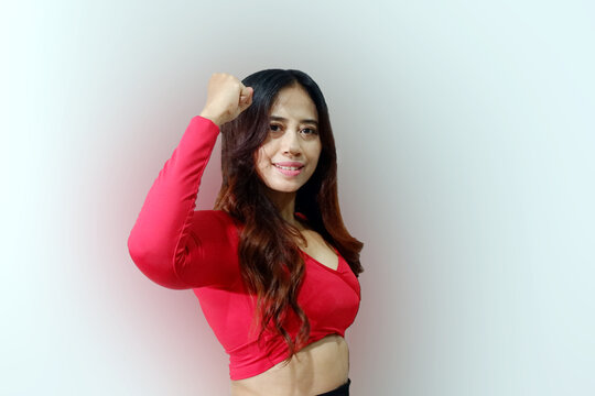 Asian woman wearing casual t-shirt standing over isolated white background showing arms muscles smiling proud. Fitness concept.