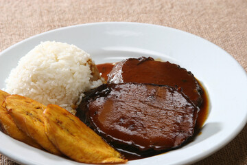 Venezuelan asado negro—slow-braising beef in deep caramelized sauce, accompanying white rice and crispy plantain slices