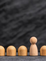 A wooden figurine stands out among rounded shapes, symbolizing leadership and uniqueness in a corporate setting.