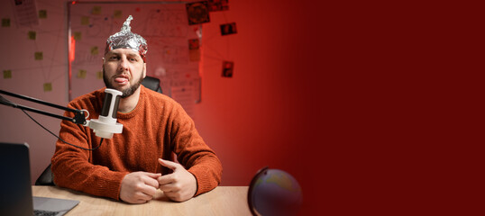 Bearded man in aluminum foil hat making faces at camera sticking out her tongue while Live...