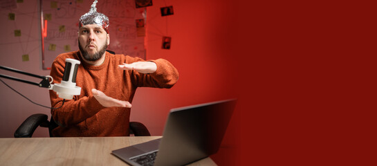 Bearded man in aluminum foil hat gesturing showing big large size sign while Live streaming,...