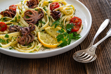 Pasta with baby octopus on wooden table	