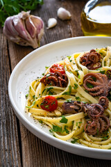 Pasta with baby octopus on wooden table	