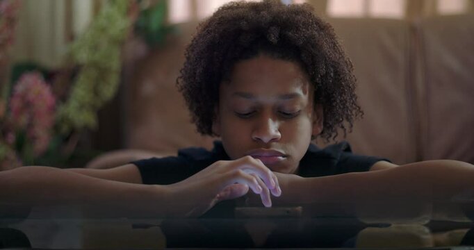Close-up of boy leaning on arms staring at smartphone, vacant expression, glass table reflection, highlighting emotional apathy and detachment from surroundings
