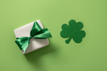 St Patricks day and March 17 concept with gift and clover leaf on green background. View from above.