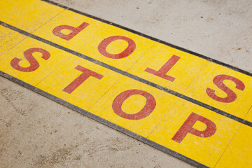 Faded yellow stop sign painted on concrete.