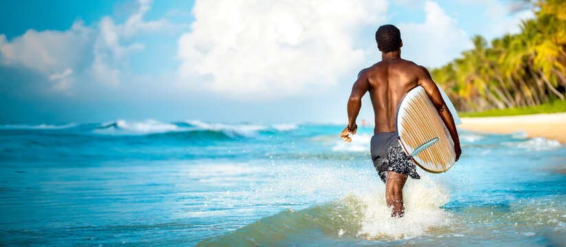 Mann mit Surfbrett rennt in die Wellen 