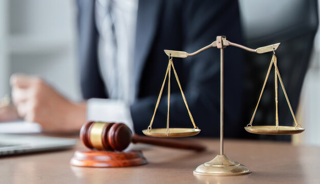 Lawyer analyzing legal documents with scales of justice and gavel on desk in modern office setting.