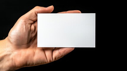 Hand holding blank white card against black background for presentation and branding