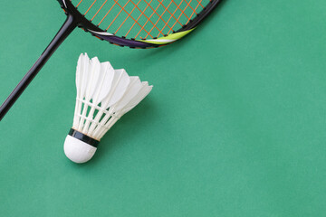 Badminton racket and white shuttlecock on green background