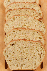 Slices of homemade bread with chia seeds are arranged on a wooden cutting board, showcasing the texture and healthy ingredients
