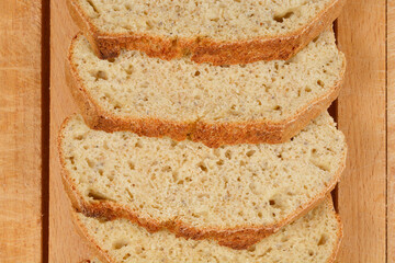 Slices of homemade bread with chia seeds are arranged on a wooden cutting board, showcasing the texture and healthy ingredients