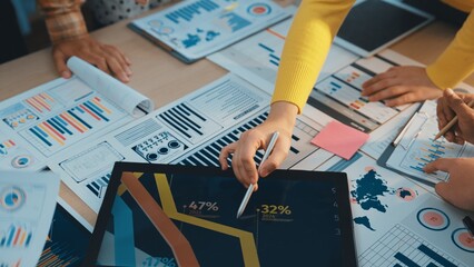 A diverse business team collaborates on financial analysis, reviewing charts and data while utilizing a tablet for insights during a strategic planning meeting in an office. SACTR