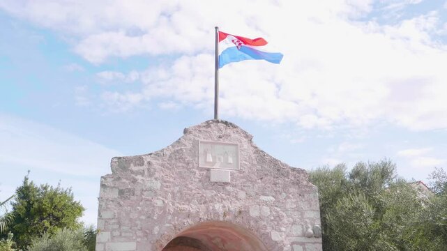 The flag of Croatia blowing above the historic town gate of Nin, Croatia