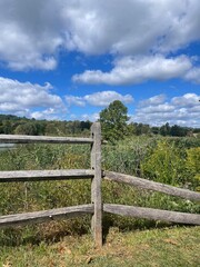 Old Weathered Split Rail Cedar Wood Fence, next to a Pond and a Grassy Meadow Field.