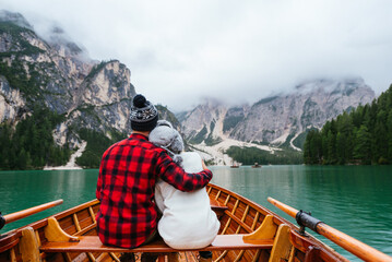 Couple of lovers on wooden boat at Braies lake on Dolomites mountains - wanderlust, travel, nature concepts