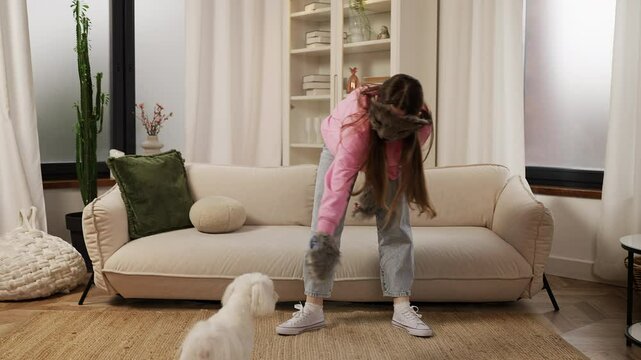 Teen girl quadrober in a fox mask plays with her adorable Maltese puppy at home