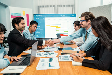Cheerful meeting room, businesspeople celebrate with handshaking. Successful project was completed before the deadline. Business partnership and collaboration in project management. Habiliment