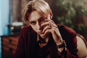 Handsome Retro Young Man Gazes at Camera, Striking a Stylish Pose with His Hand, Exuding Vintage...
