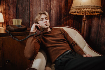 handsome modern guy loves vintage while sit in old rustic room with analog telephone and call with...