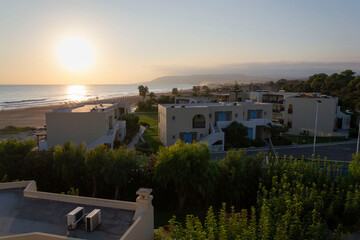 Blue and white tourist apartments on the beachfront during sunrise in Crete, Greece, sunny summer day
