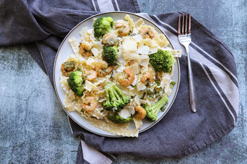 Close up of shrimp and broccoli pasta on plate over light stone background. Tasty dish for dinner. Top view, flat lay